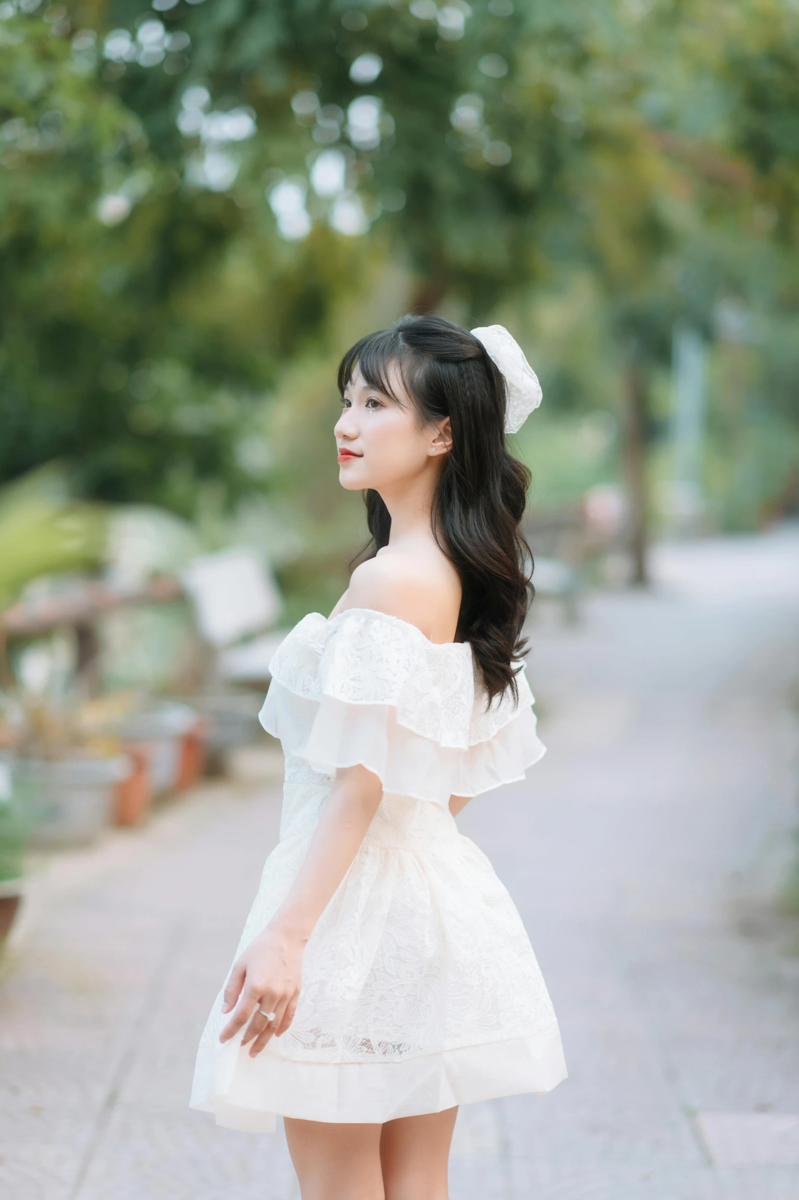 an asian woman with long dark hair in a short dress and a flower in her hair