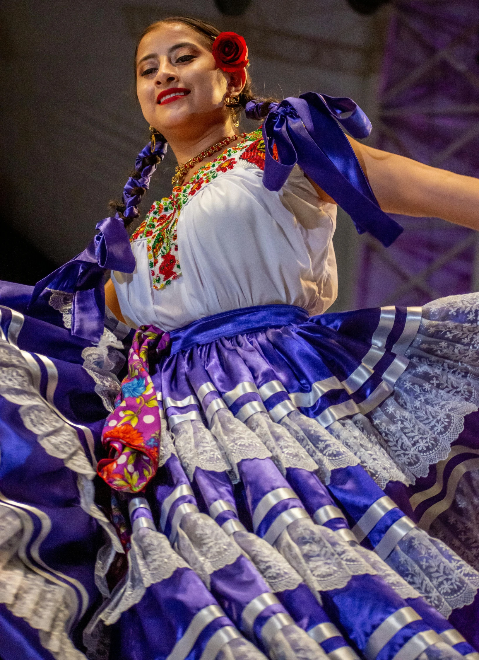 a woman in a dress with ribbons dancing on stage