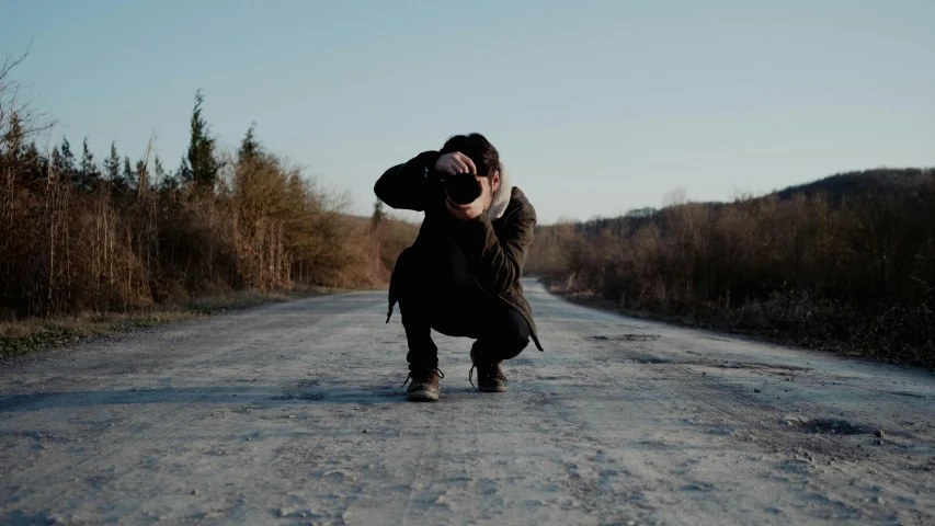 a woman walking down the middle of a dirt road