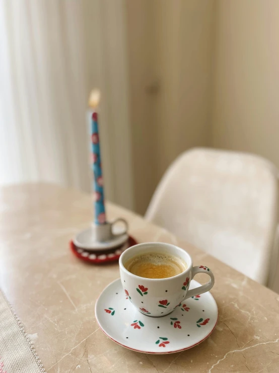 coffee cup next to a lit candle on the table