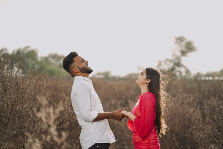couple in red and white clothes holding hands in front of brown grasses