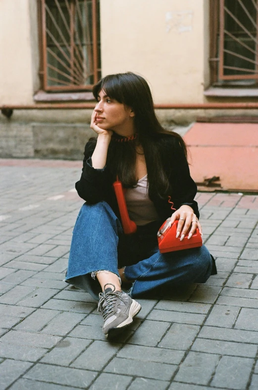 a young lady sitting on the street with a handbag