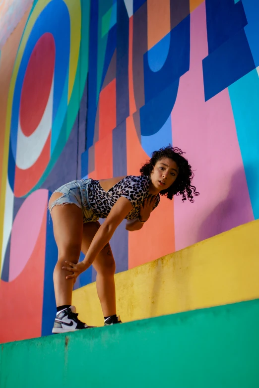 a beautiful young woman standing on a brightly colored wall