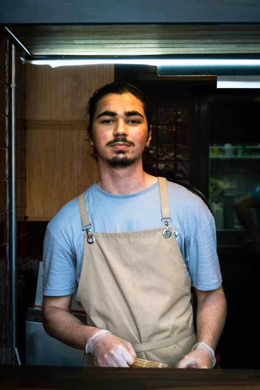 a young man in aprons stands behind the counter