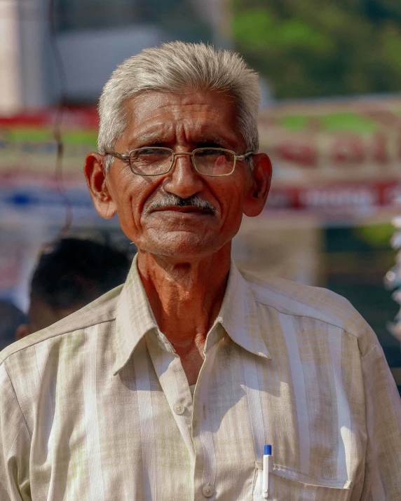 an elderly man wearing glasses in front of a building