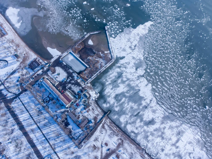 a body of water with buildings in the foreground covered in ice