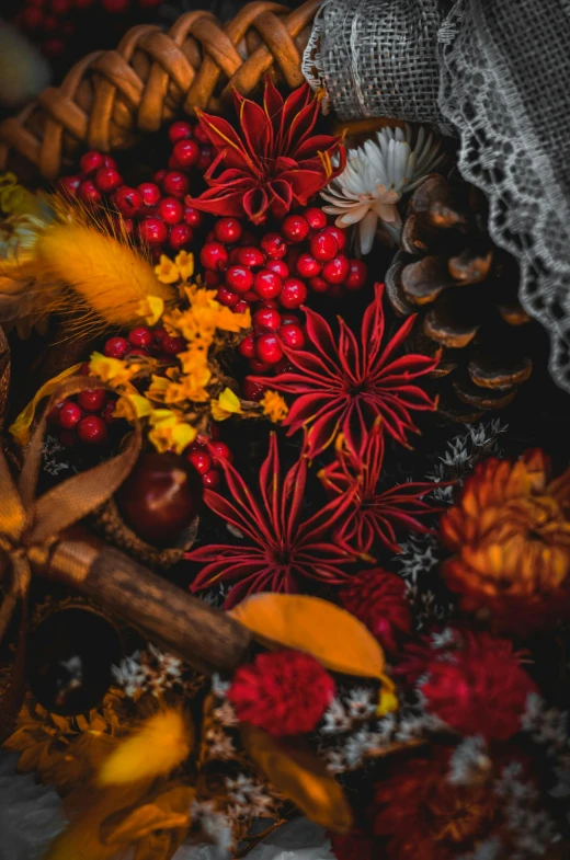 some oranges, red berries, and fall leaves in a basket