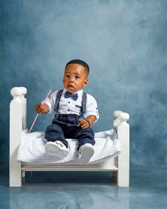 a black baby sitting on a small bed