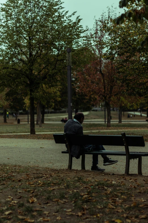 man sitting alone on a park bench in autumn