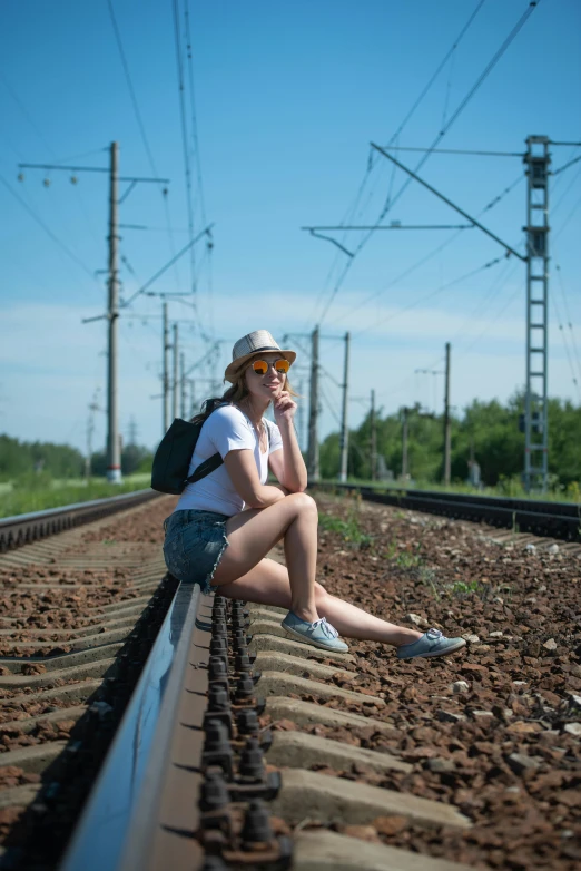 a woman sitting on the railroad tracks smoking a cigarette