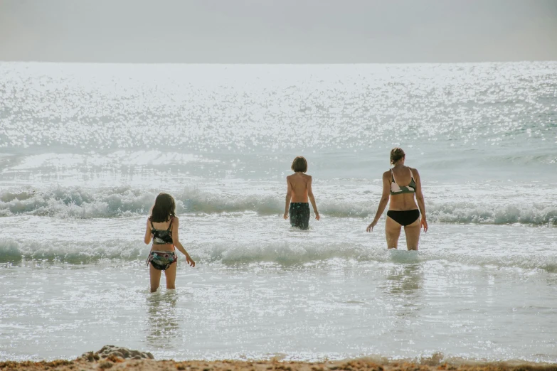 three girls are standing in the ocean water
