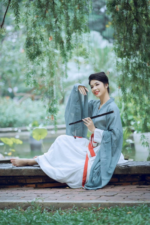 the woman in an oriental dress poses on a concrete bench