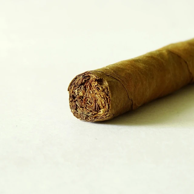 a close up of the end of a cigar that is on a white surface