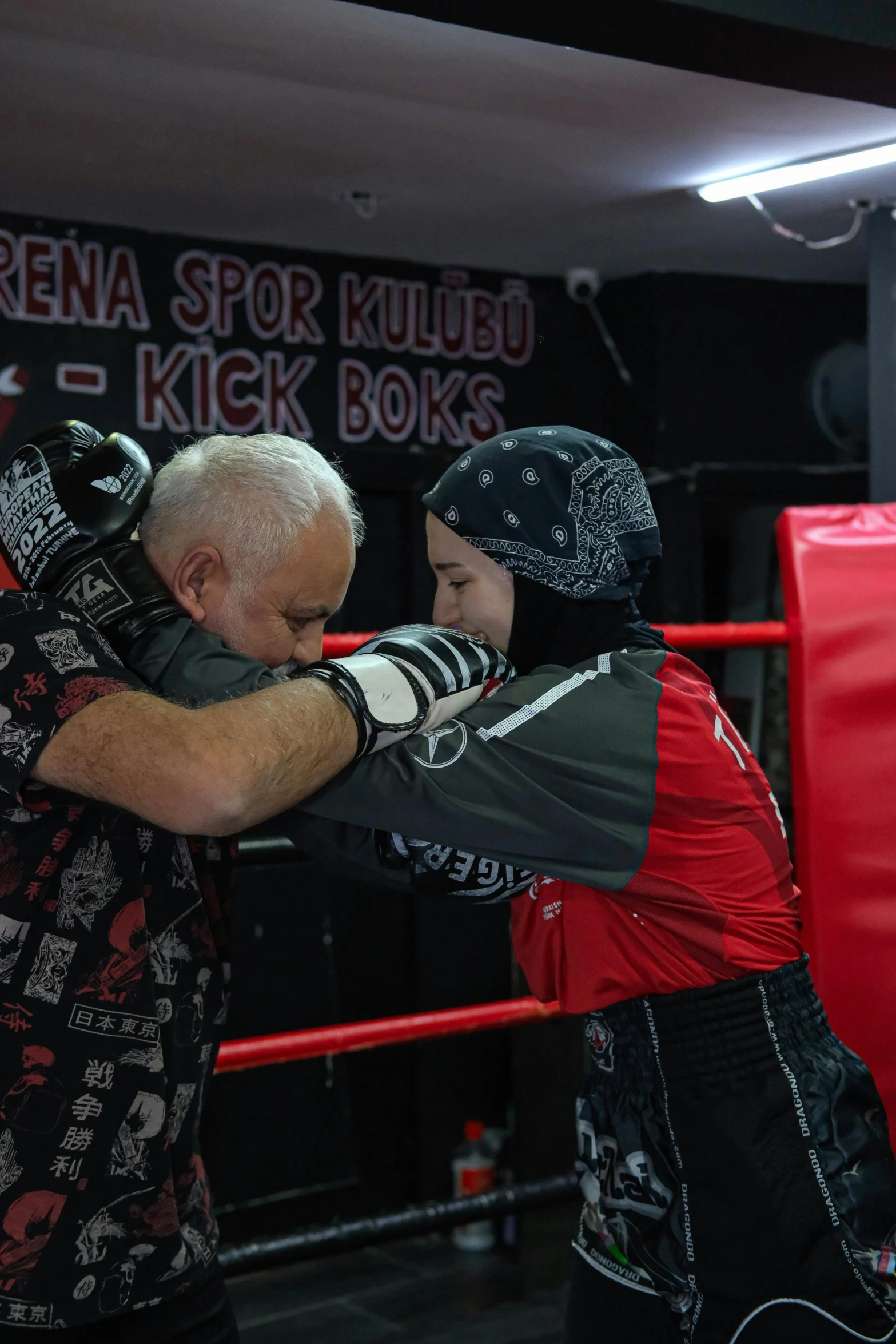 a man is standing by a boxing ring with his arm around a woman