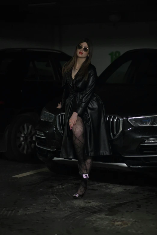 a woman sitting on the front of a car wearing sunglasses