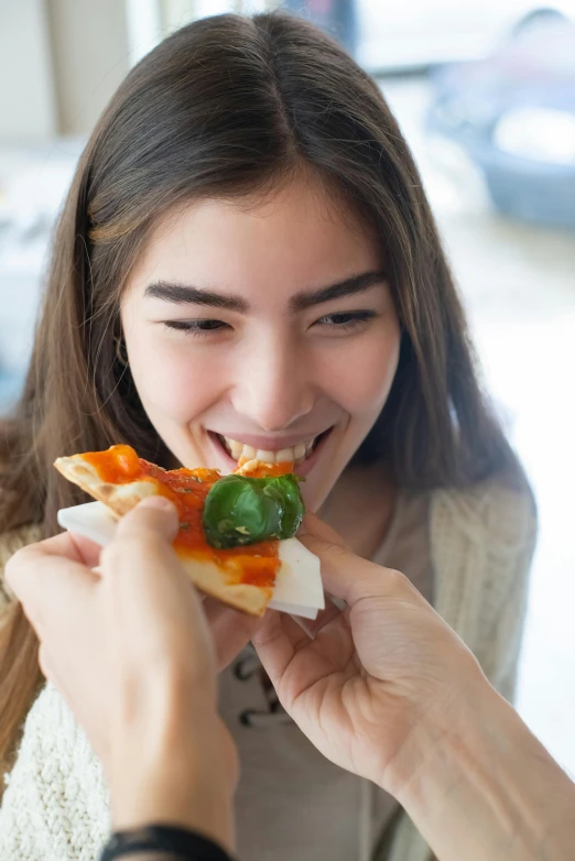 a woman that is smiling holding a pizza in her hand