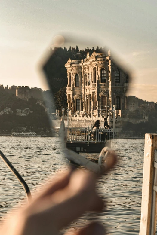 a view through a pair of scissors of water and the reflection of a house on the other side