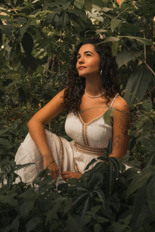 a beautiful young woman sitting in the leaves of trees