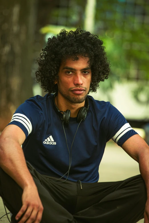 a man in headphones sitting by some trees