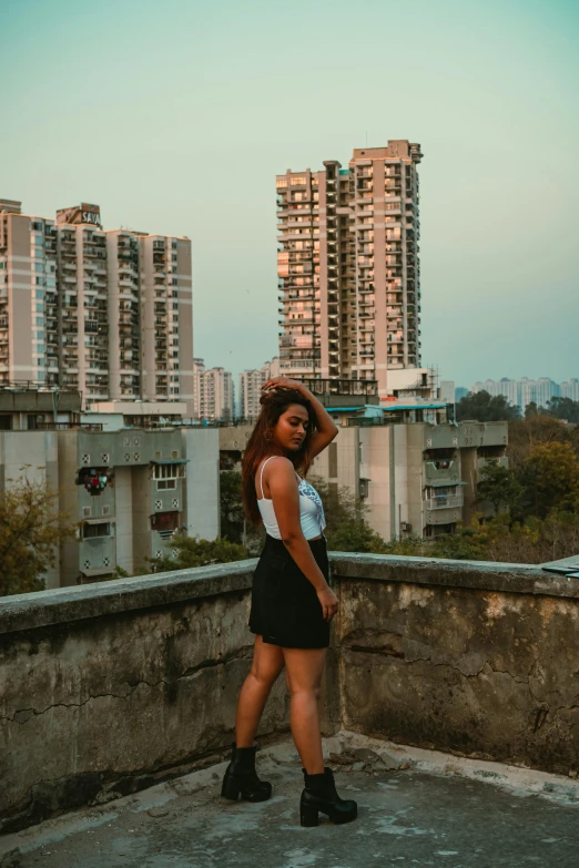 a woman posing on a concrete wall next to tall buildings