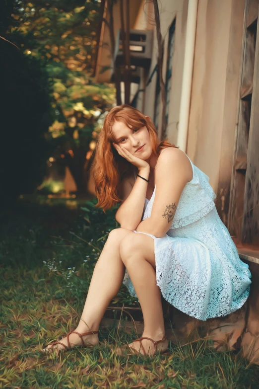 a woman in a white dress sits on the side of a house