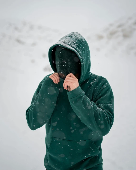 a person in a green jacket is wearing a snowboarder hoodie