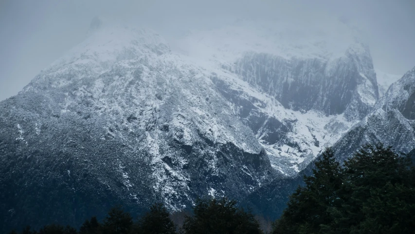 mountains are shown in a misty scene with snow on them