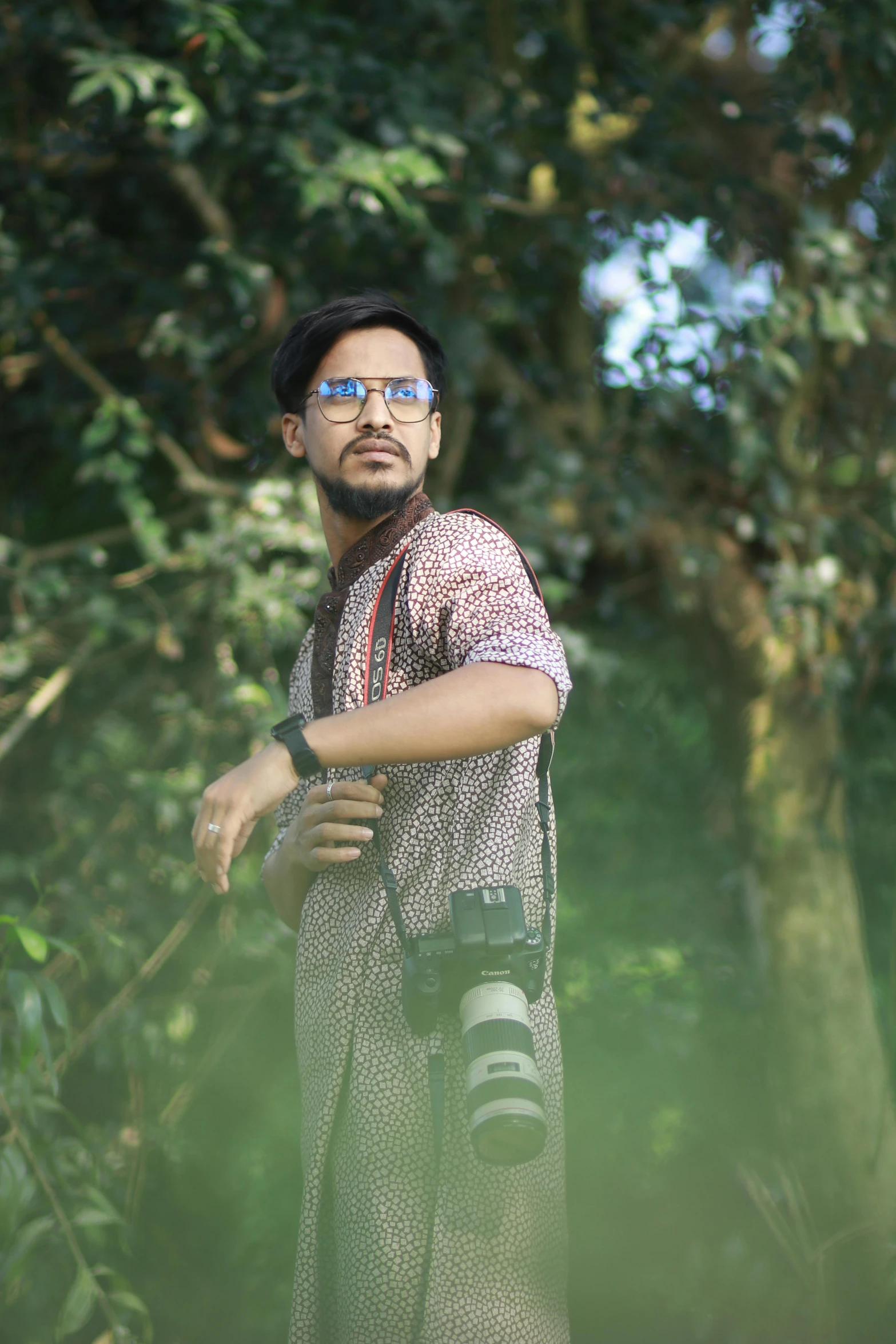 a man standing next to a tree with camera on his shoulder