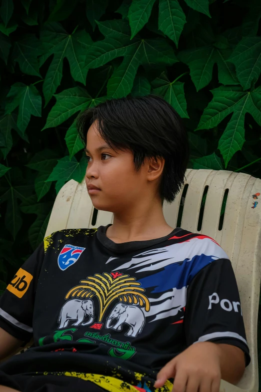 a small child sitting on a chair in front of a bush