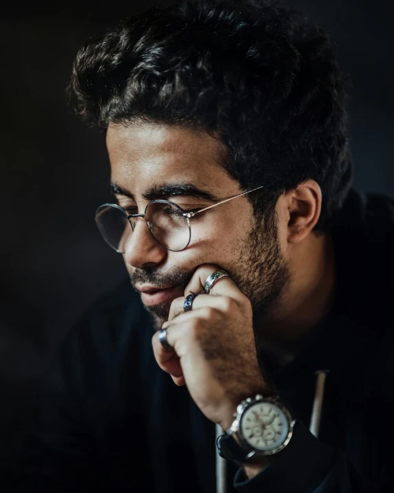 a man with black hair wearing glasses and a watch