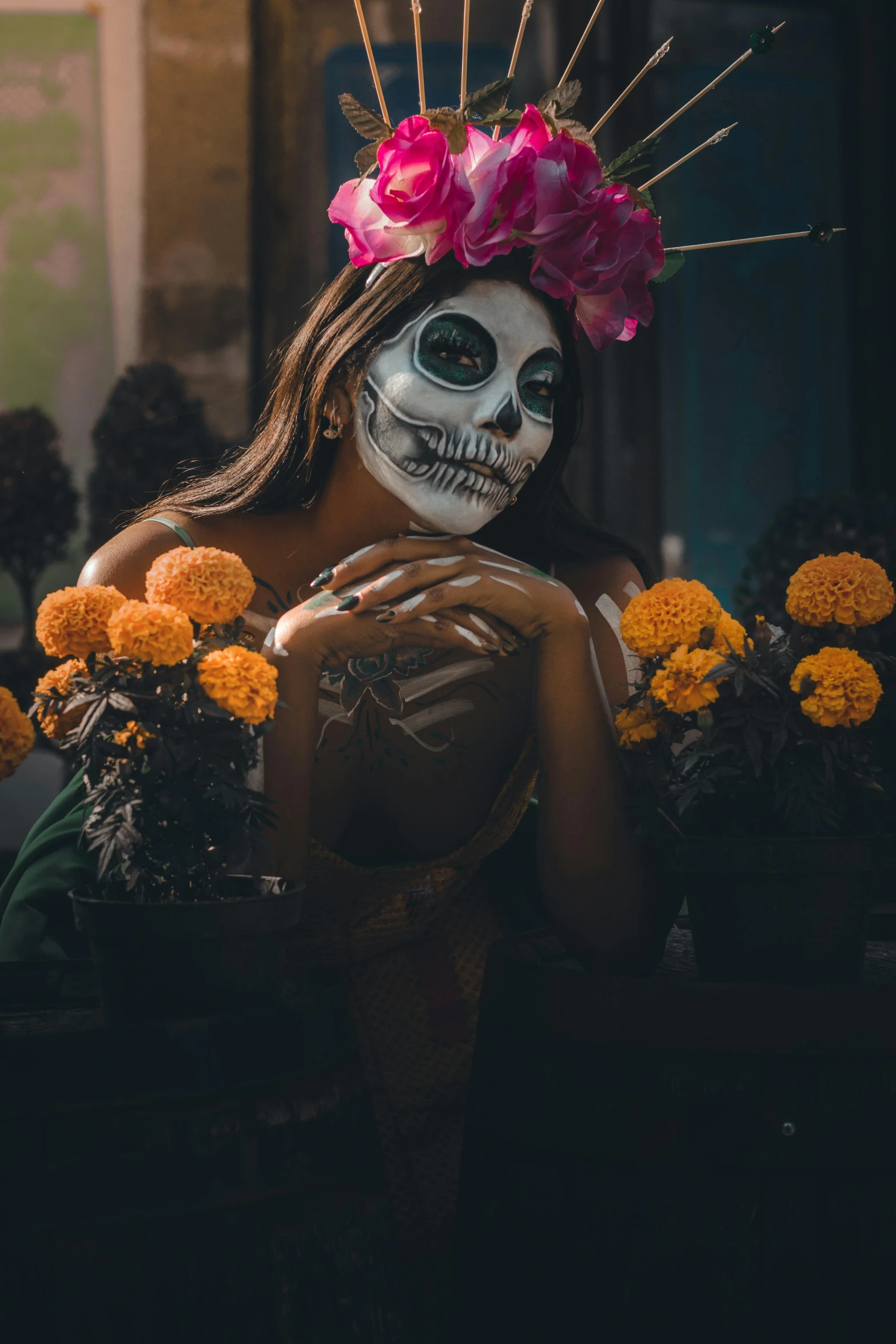 a skeleton wearing flowers and head dress poses in front of some skulls