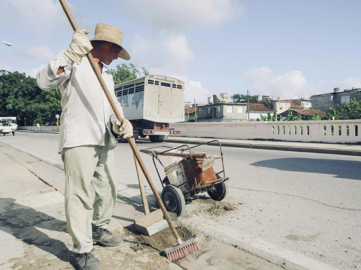 an old man with a broom is shoveling dirt