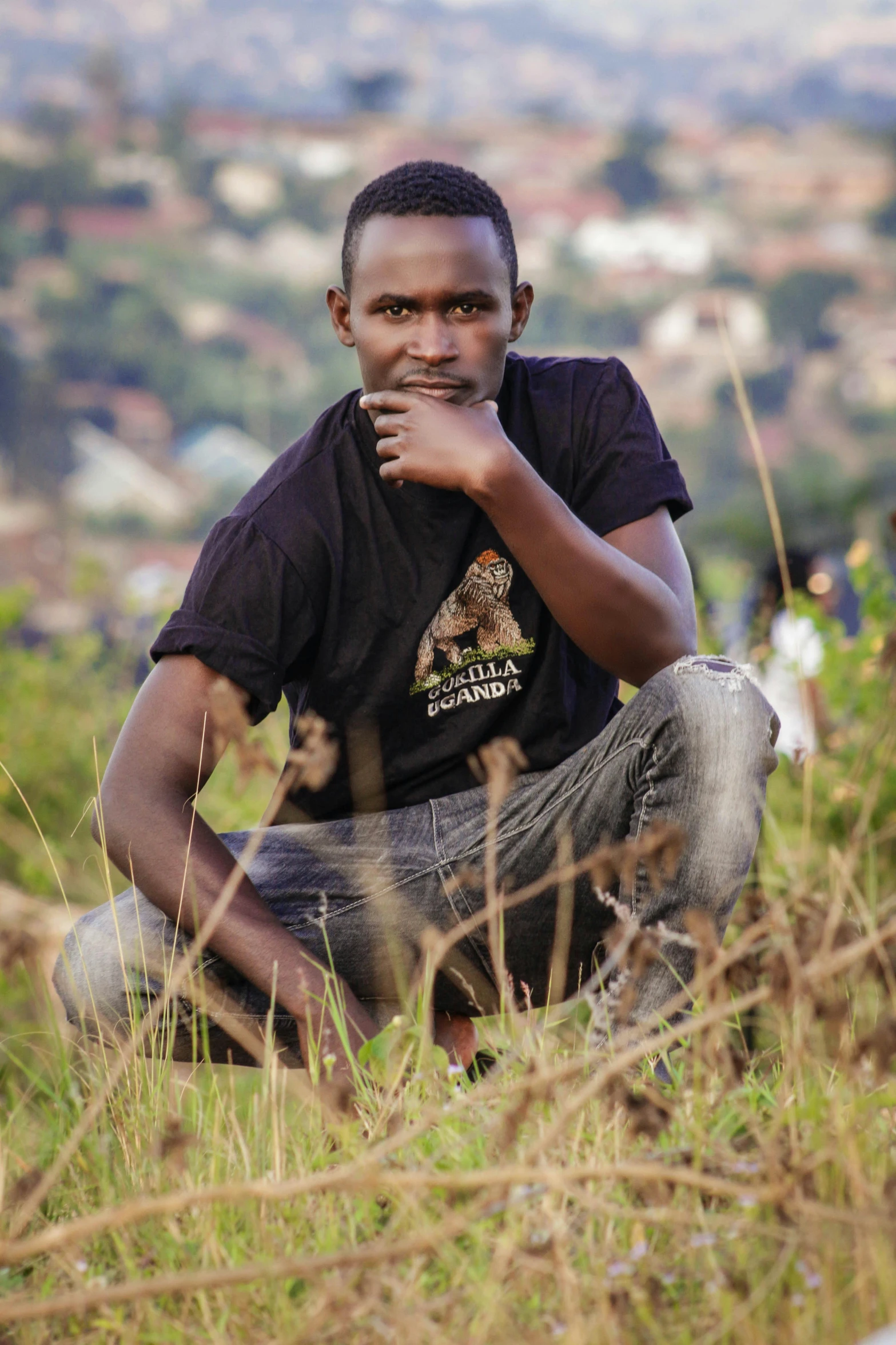 a man in a black shirt sits in tall grass