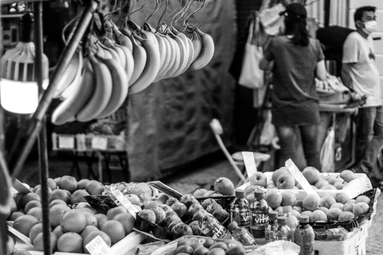 people in black and white standing behind fruit stand