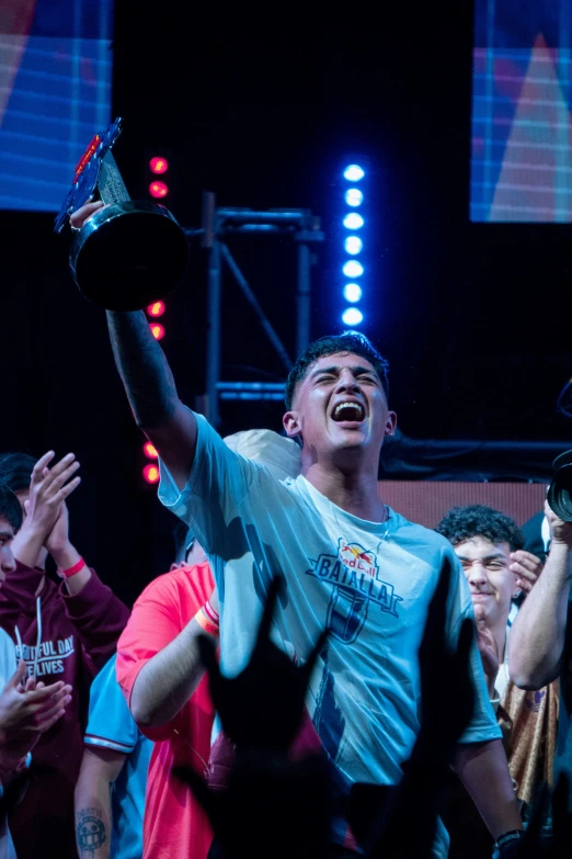 man holding up a cup in the air on stage