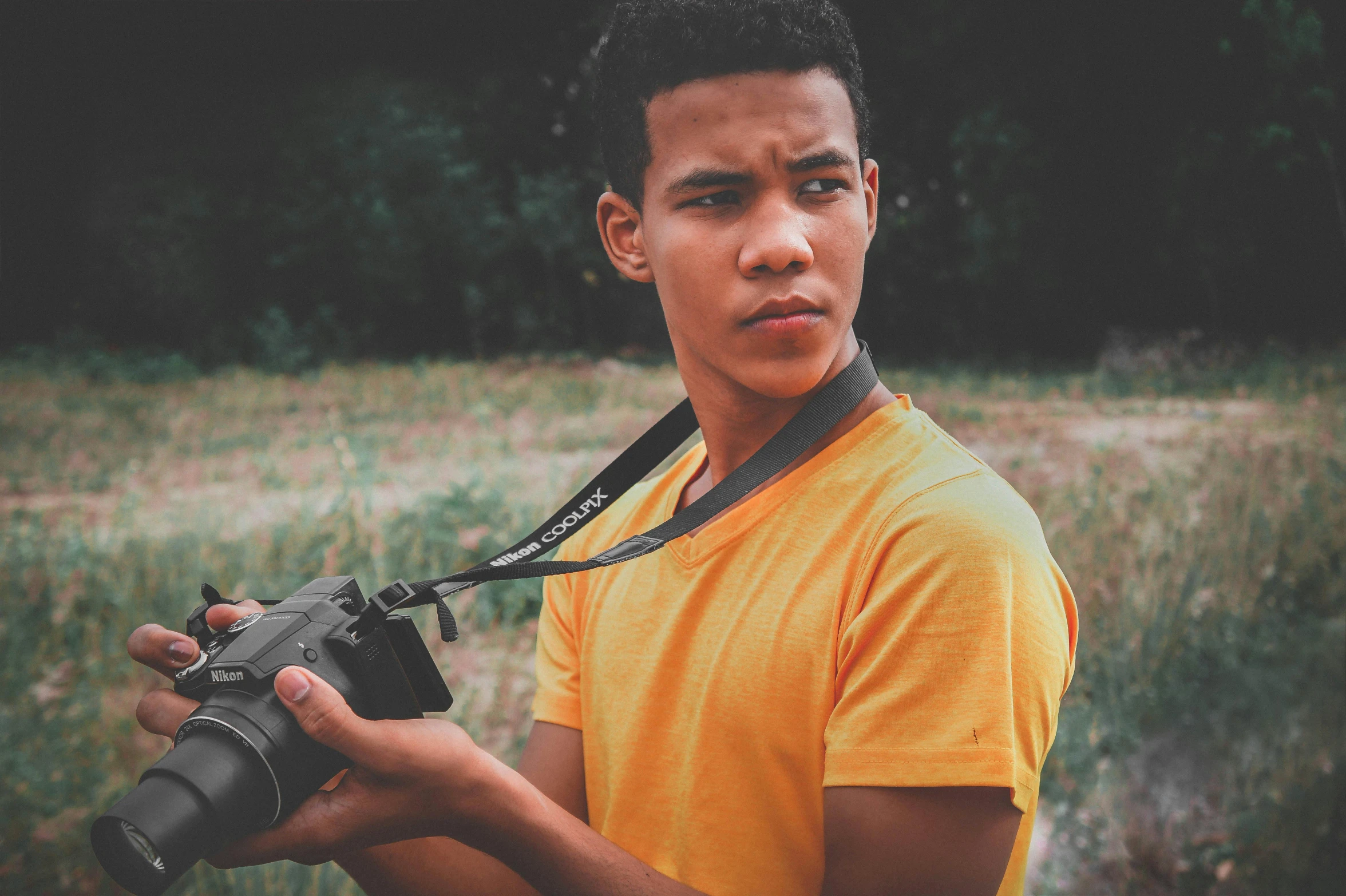 a boy in an orange shirt is holding a camera