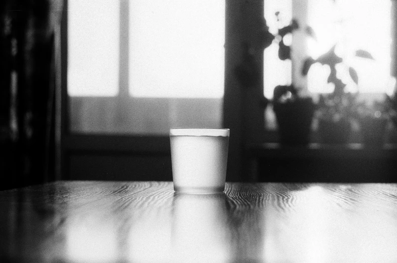 a coffee cup sitting on a table with someone holding a stuffed animal