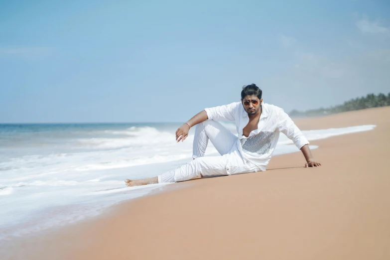 a man sitting on top of a sandy beach