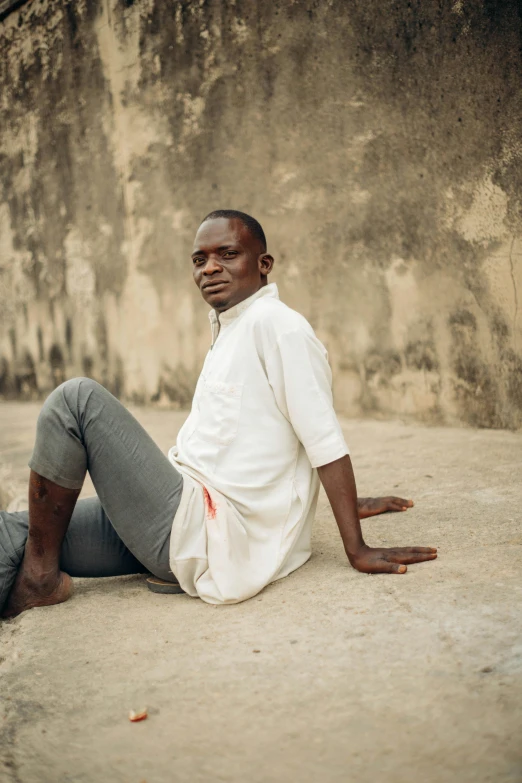 an african american man sitting against a wall