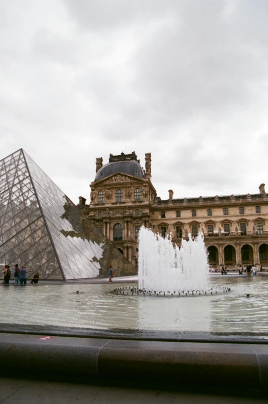 the pyramid is surrounded by fountains in front of a building