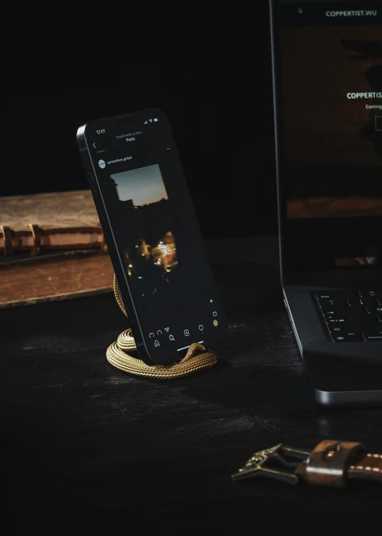 cellphone on a phone stand with a laptop nearby