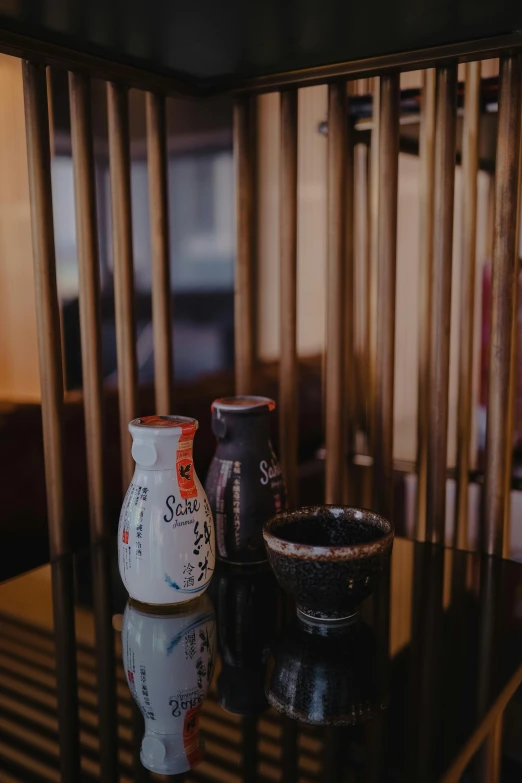 small vases sit on a glass table next to bamboo shutters