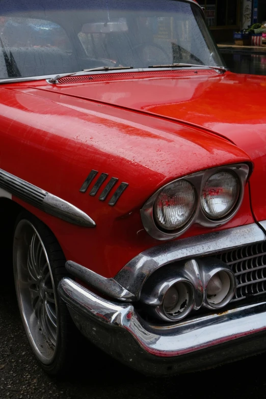 an old red car parked in the parking lot