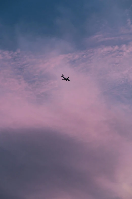 the airplane is flying in a blue and pink sky