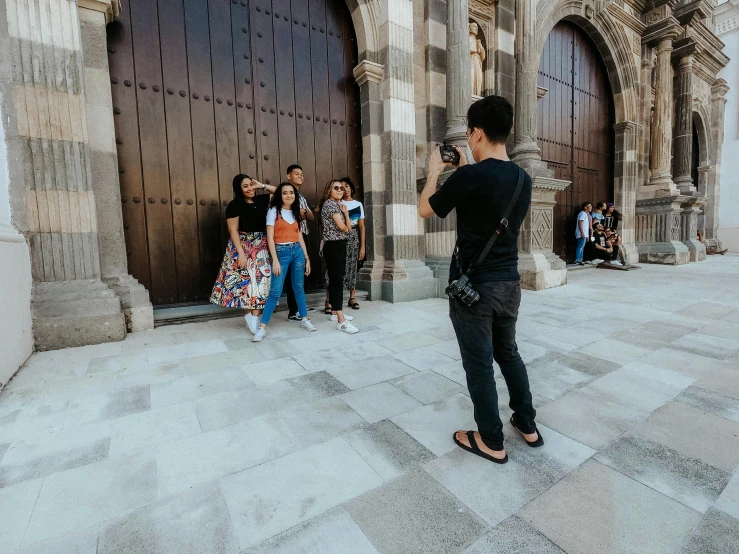 young man taking pograph of two young people next to doors