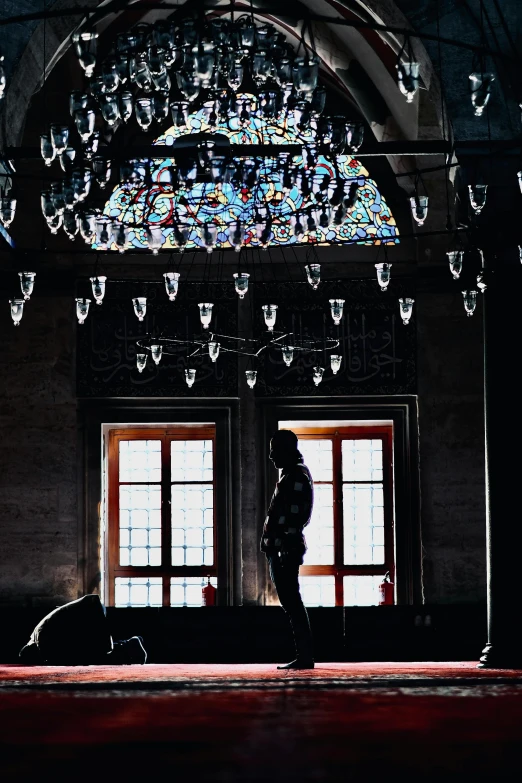 a man in black standing by a set of windows