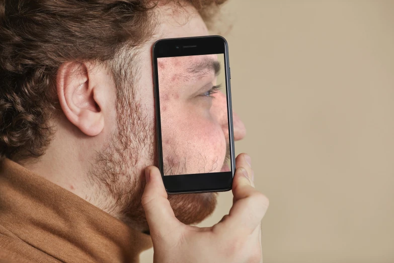 a person holding up a smart phone to their face with a slightly open face