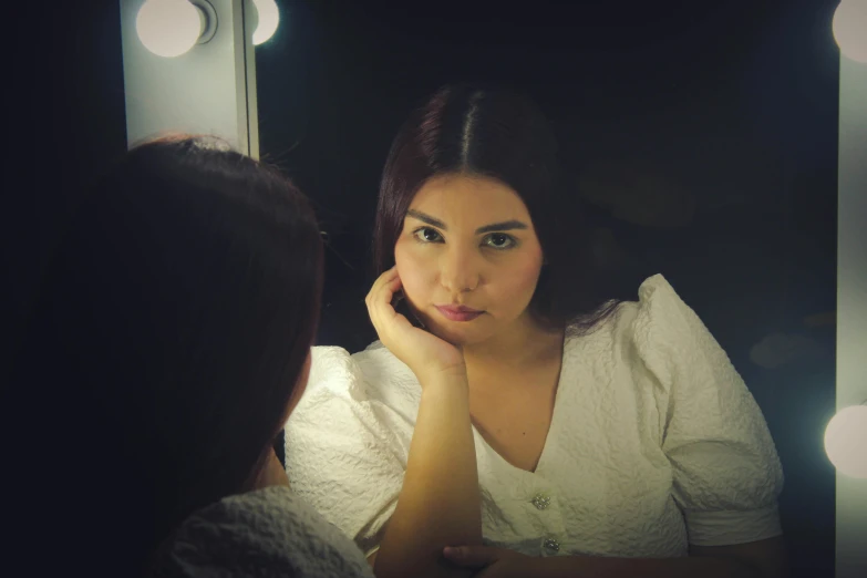 a woman with dark hair looking into a mirror