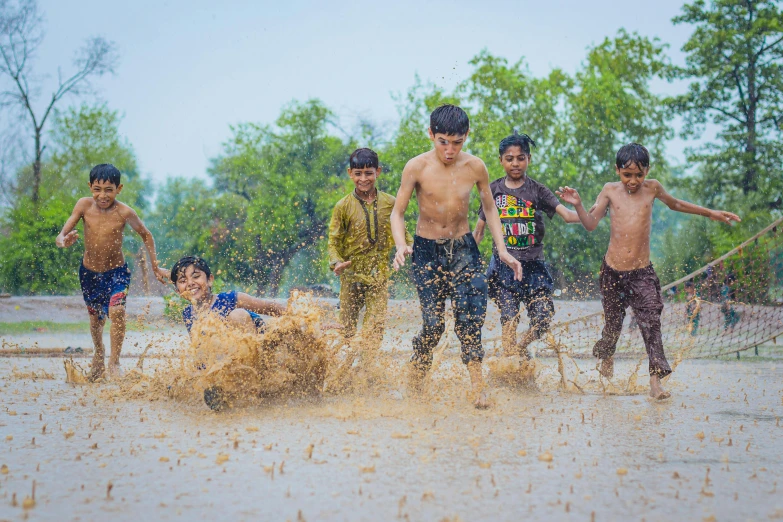 group of boys and a woman playing in mud