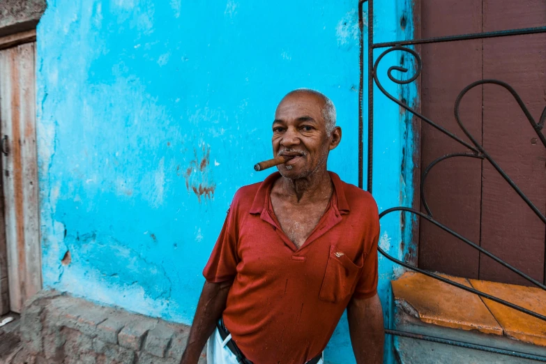 an old man standing outside of his house with a cigarette